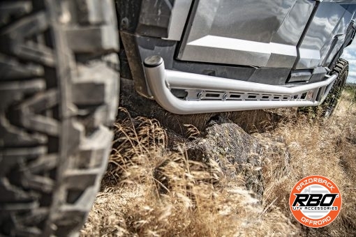 A utv with nerf bars driving over rocks