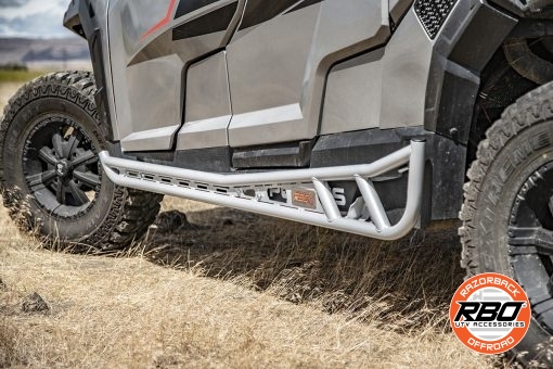 A side by side is parked on the side of a dirt field